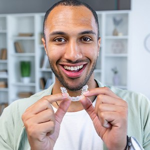 a patient holding his Invisalign aligner
