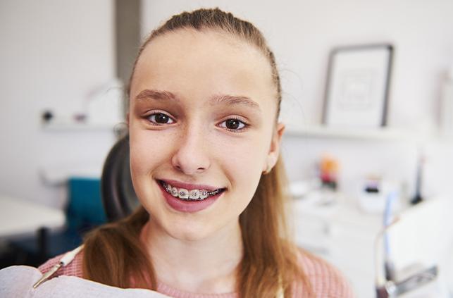 Young girl with braces smiling in dental chair