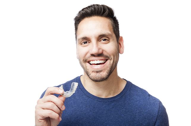 Smiling man holding an orthodontic aligner tray
