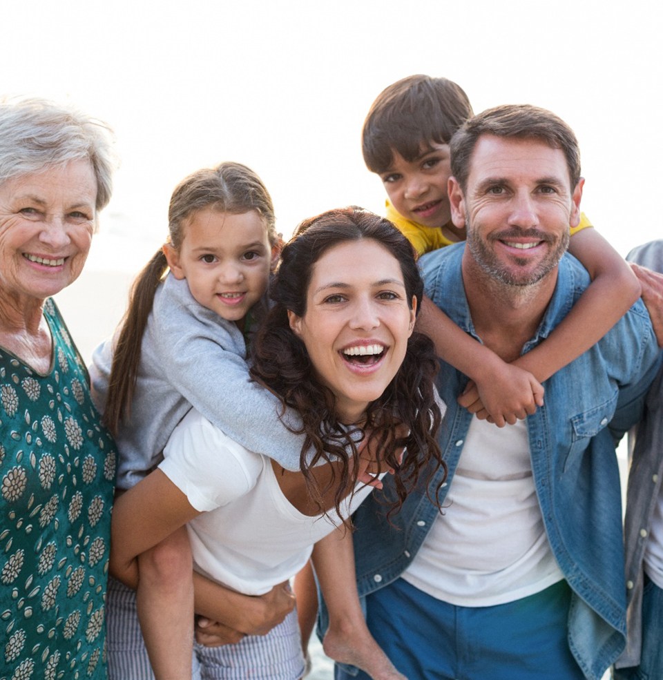 Smiling family on the beach who are pleased with their United Concordia orthodontist in Lawrence 