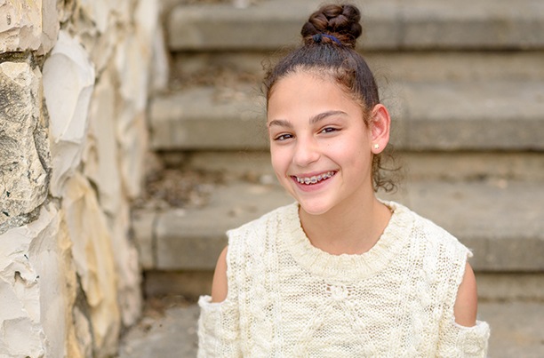 Young girl smiling while wearing braces (United Concordia Coverage and Availability IMAGE)