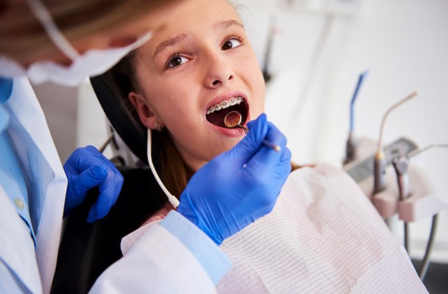 Orthodontist checking young girl's braces