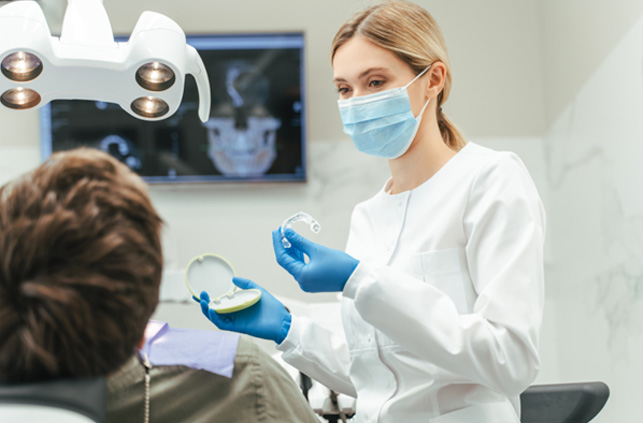 Dentist showing patient clear aligner in treatment room