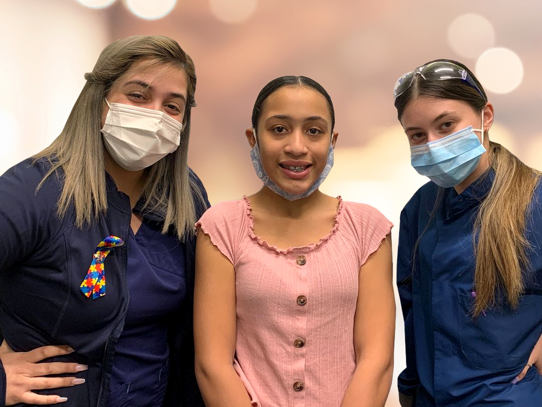 Two orthodontic team members and young patient smiling together