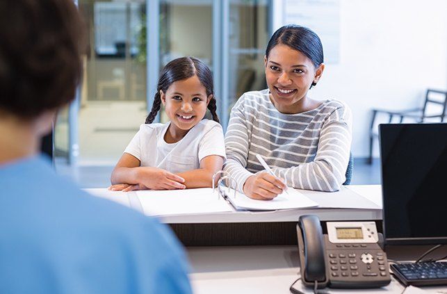 Mother and daughter completing dental insurance forms at reception desk