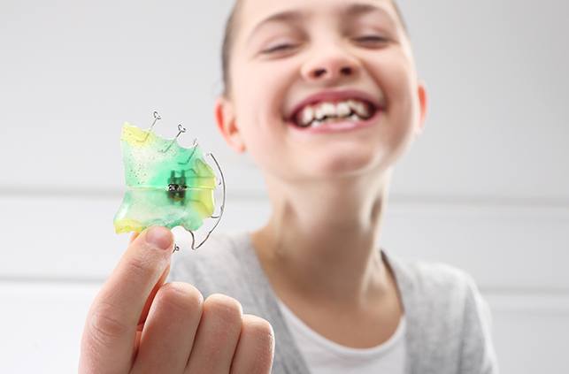 Young girl holding retainer and laughing