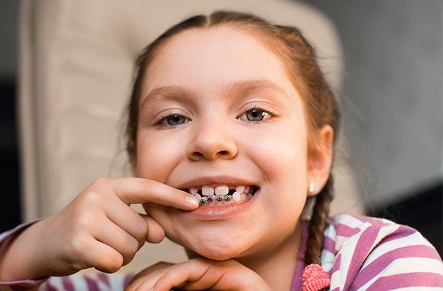 Young girl pointing to her pediatric orthodontics appliance