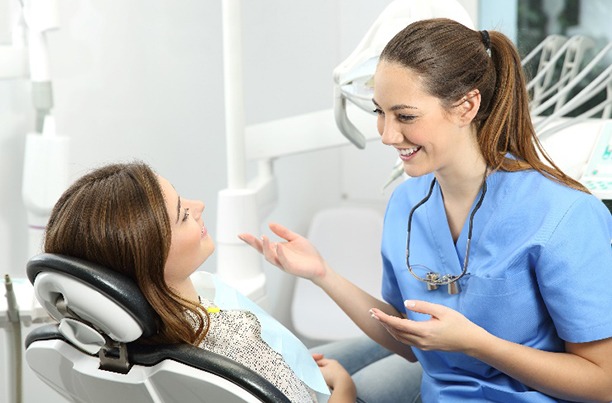 Smiling orthodontic assistant talking to patient in treatment chair