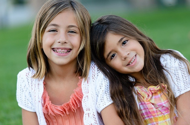 Two young girl receiving dentofacial orthopedics treatment smiling