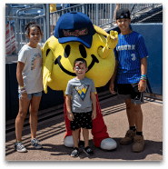 Children posing with smiley face mascot at sports event