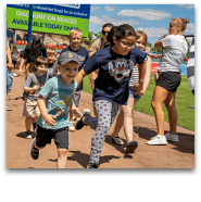 Two children running on baseball field