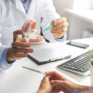 a dentist examining model teeth with braces