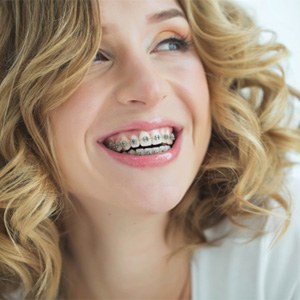 a patient with braces smiling in Lawrence