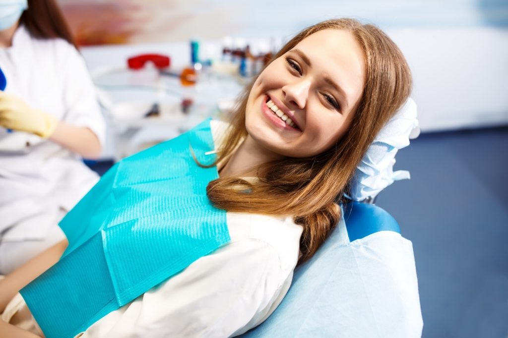 Young girl with straight teeth smiling in treatment chair