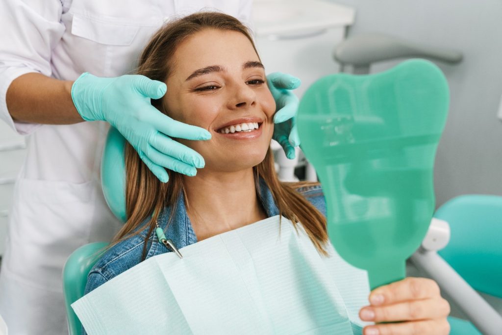 Woman with straight teeth smiling at reflection