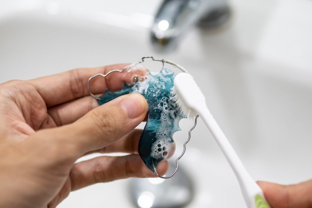 Closeup of patient brushing their retainer