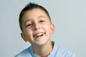 Smiling boy with braces with baby teeth