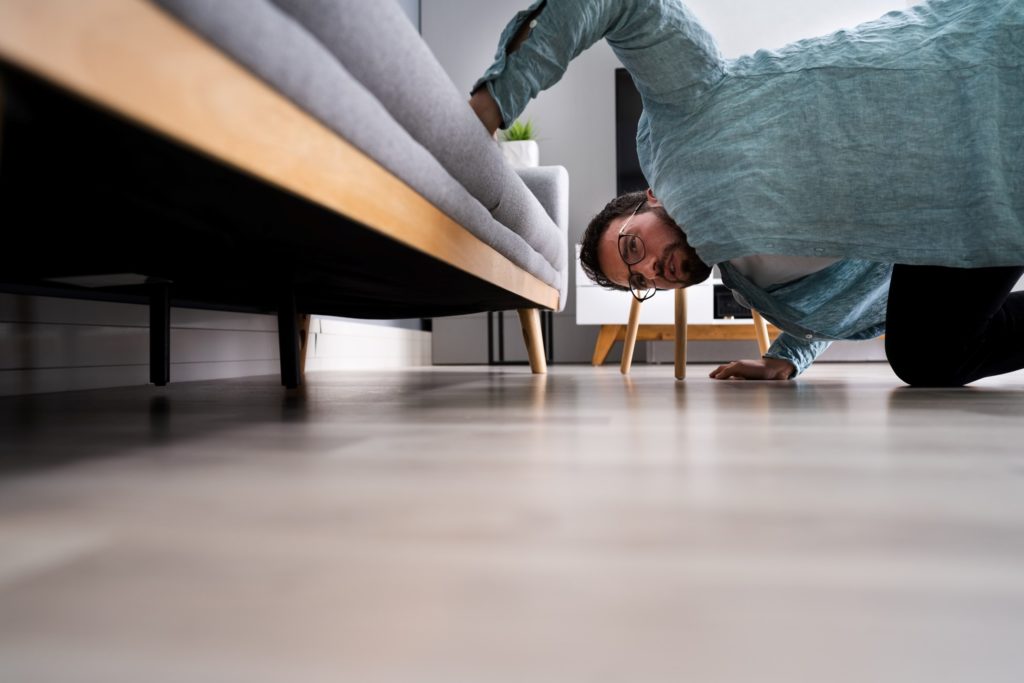 Man looking under couch for Invisalign aligner