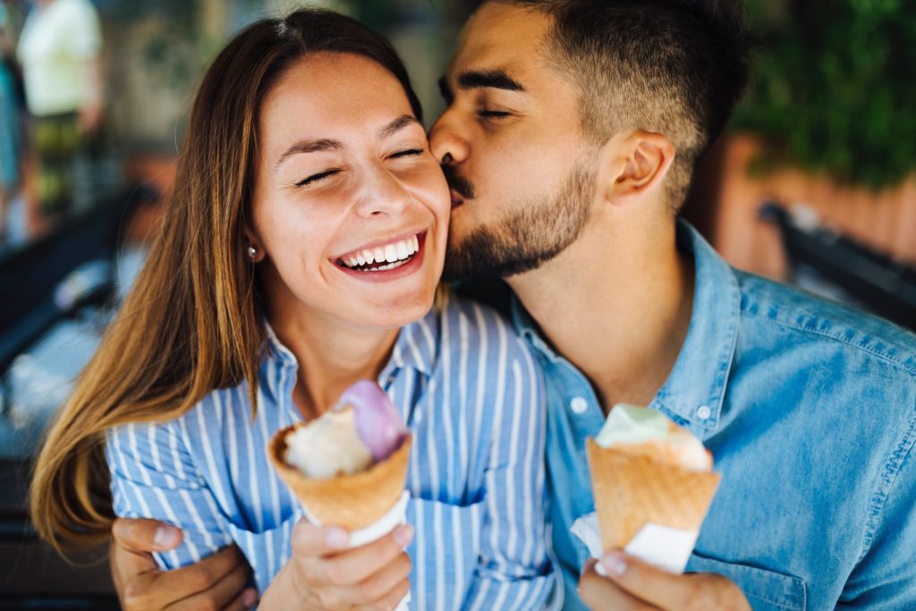 Man kissing woman on cheek during ice cream date