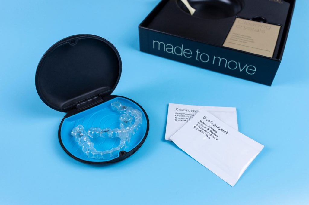 Invisalign cleaning crystal packets next to Invisalign aligners