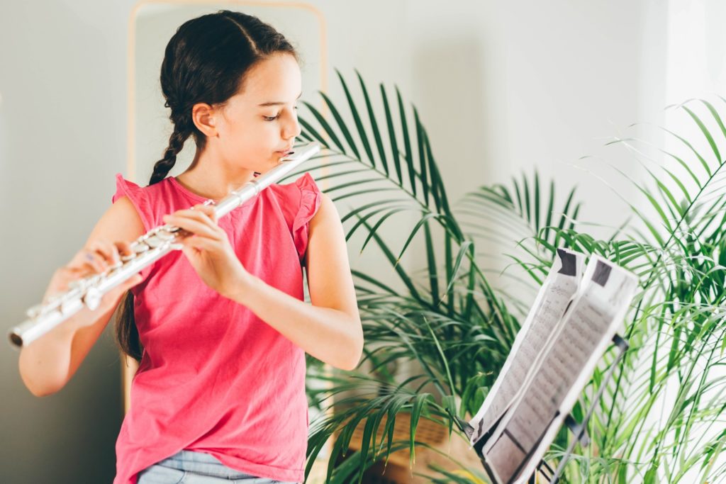 Young girl practicing flute at home