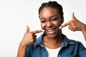 Smiling girl pointing to her braces in Lawrence