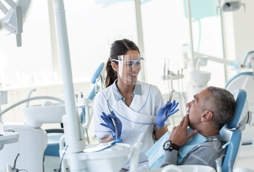 Smiling dentist talking to patient in treatment room