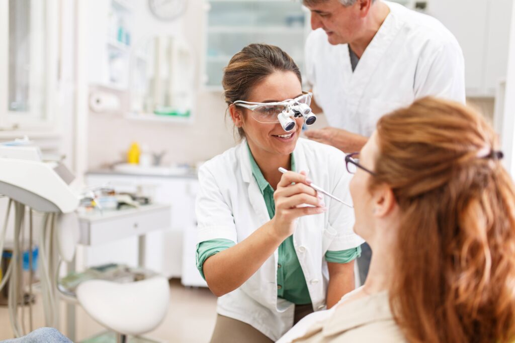 Smiling orthodontist looking at patient's teeth